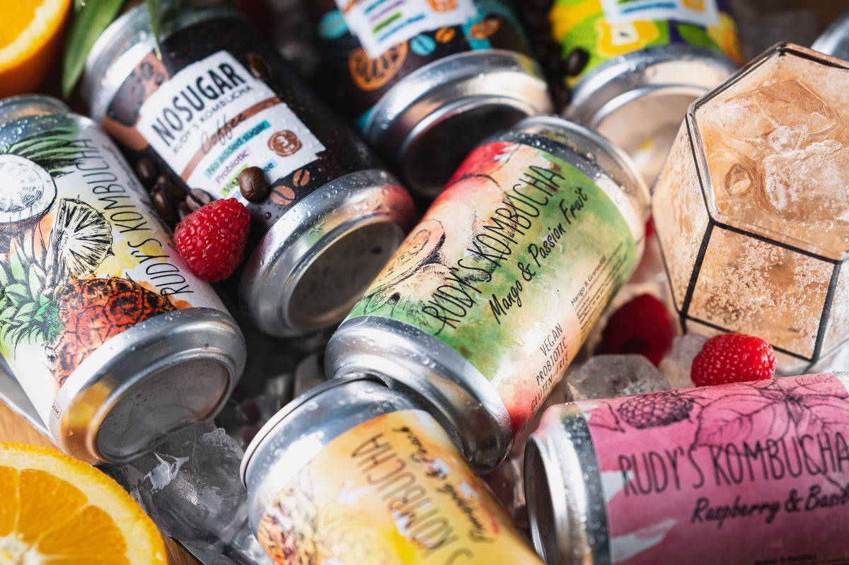 Rudy's Kombucha cans on ice with fresh fruit